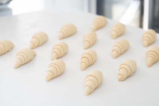 Pâte feuilletée en forme de croissants disposée sur un plan de travail blanc.