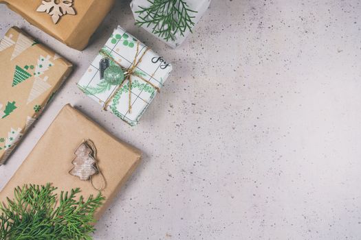 Cadeaux soigneusement emballés avec du papier kraft et des décorations naturelles sur une surface neutre.