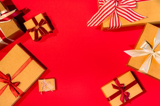 Cadeaux soigneusement emballés avec des rubans sur un fond rouge, évoquant l'art d'offrir avec élégance.