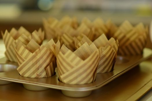 Moules à cupcakes en papier rayé disposés dans un moule en métal, prêts pour la cuisson.