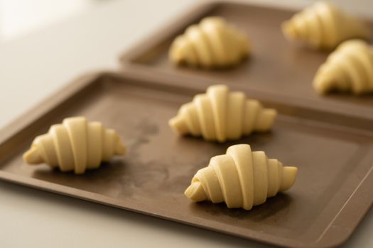 Croissants en pâte feuilletée express Choumicha prêts à cuire sur une plaque de cuisson.