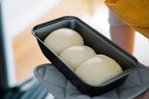 Pâte à brioche moelleuse en forme de boules dans un moule, prête à cuire.
