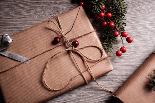 Cadeaux soigneusement emballés avec du papier kraft, décorés de ficelle et de baies rouges sur une table en bois.