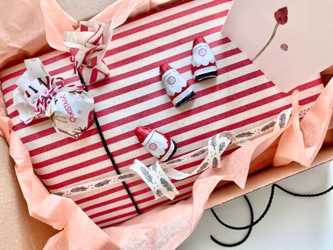 Cadeau soigneusement emballé avec du papier rayé, décoré de petits objets et d'un message sur une carte.
